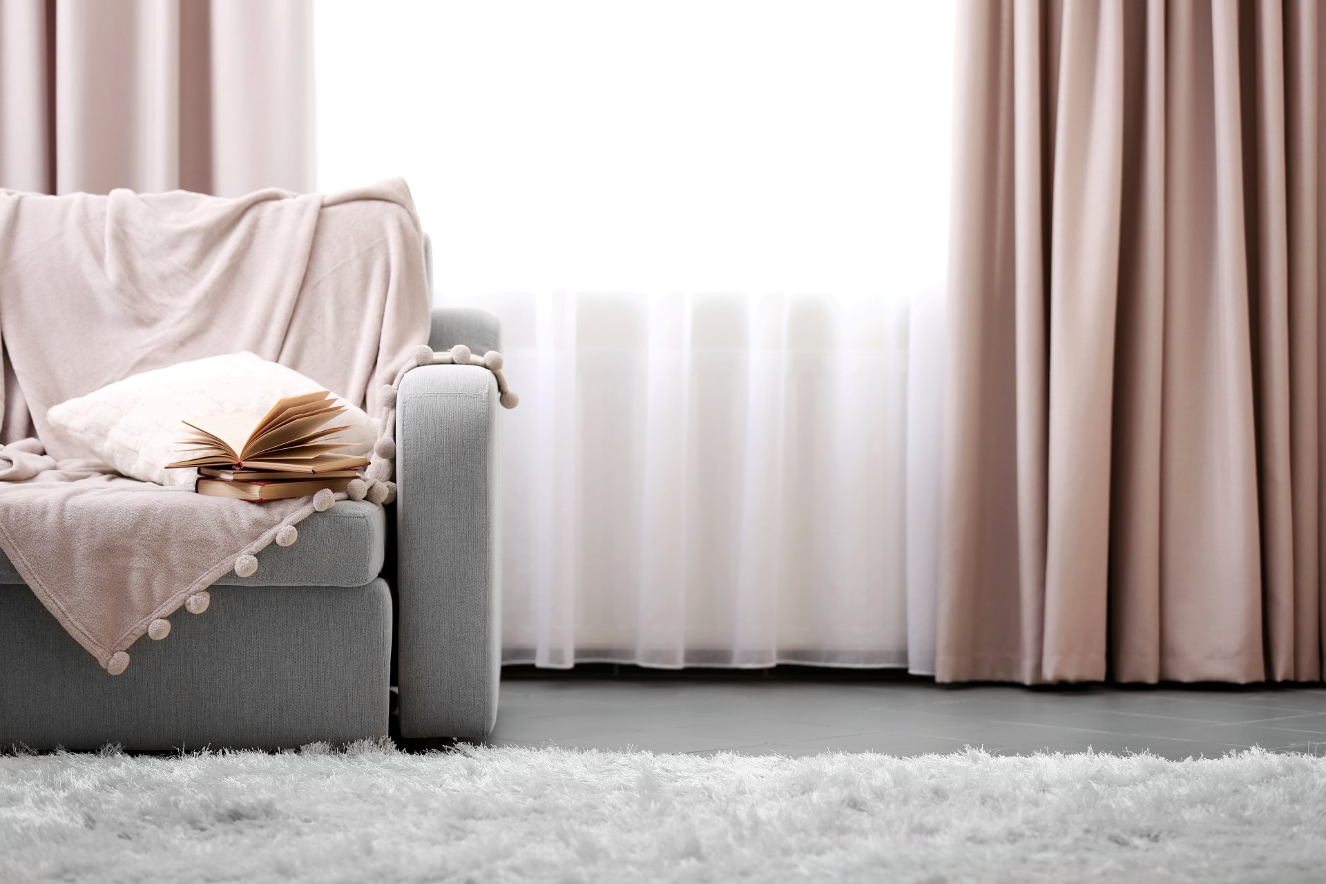 Opened Book On Comfortable Sofa Against Window In The Room